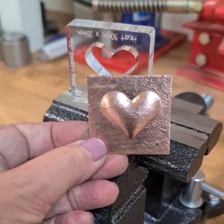 image shows a finished domed heart shape in copper sheet with the silhouette die and bench vise used in the background